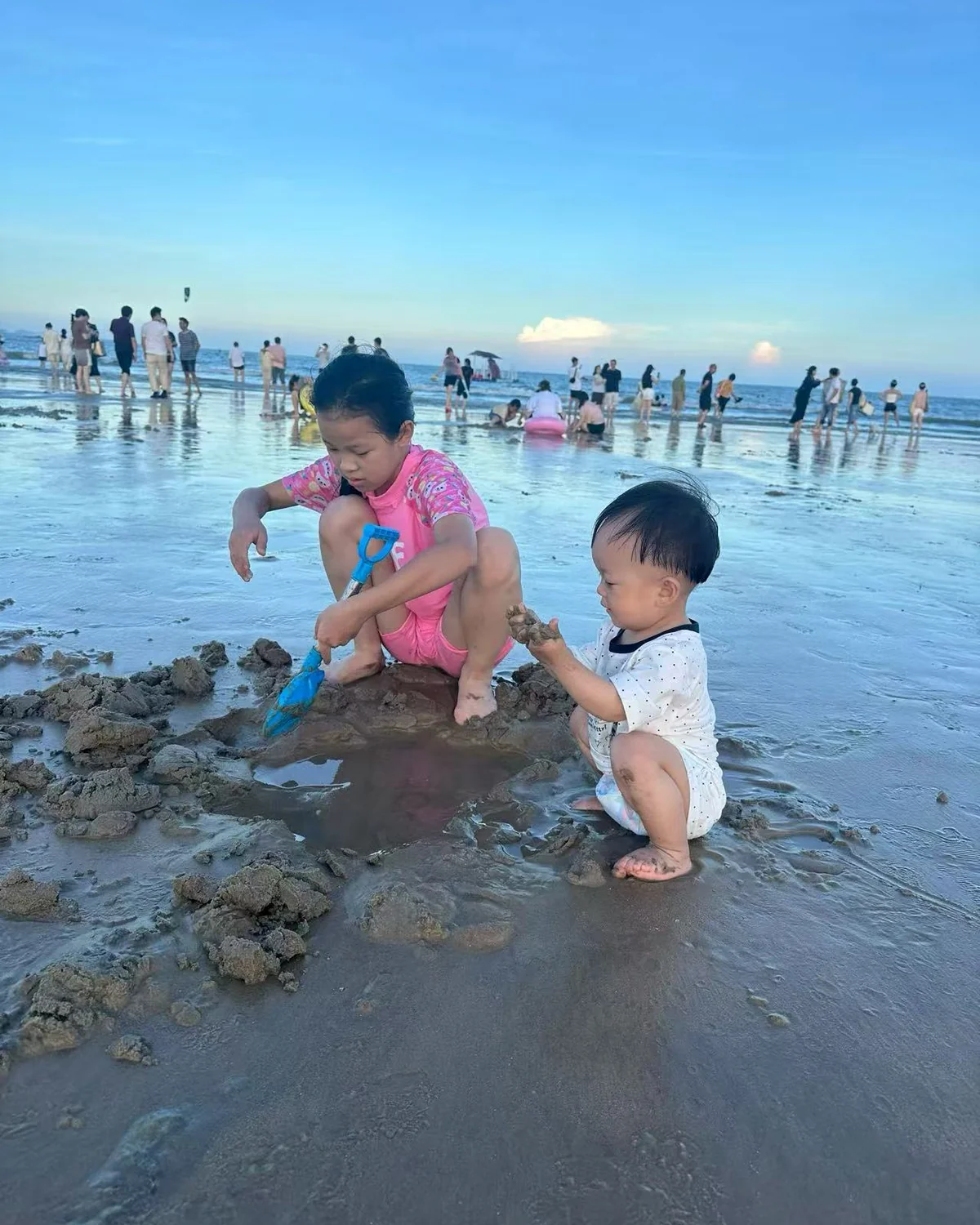 两个孩子在海边一起挖沙和观察自然的真实生活照片